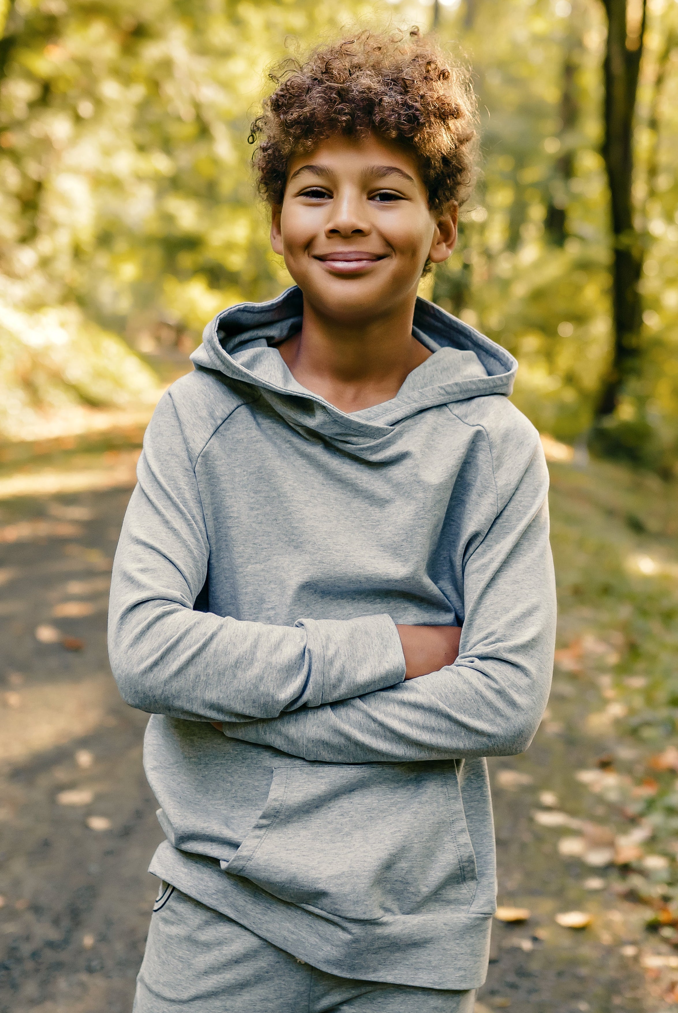 Person wearing a gray hoodie standing in a forest